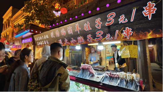 汗巴扎夜市“烤肉哥”攤位氛圍十足，引得游客紛紛購買?？κ彩腥诿襟w中心記者 董曉 攝