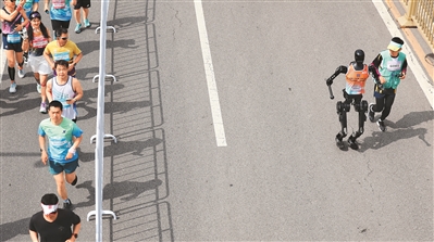 參賽選手與天工隊選手天工Ultra（右二）在2025北京亦莊半程馬拉松暨人形機器人半程馬拉松賽中。 新華社記者 曹 燦攝