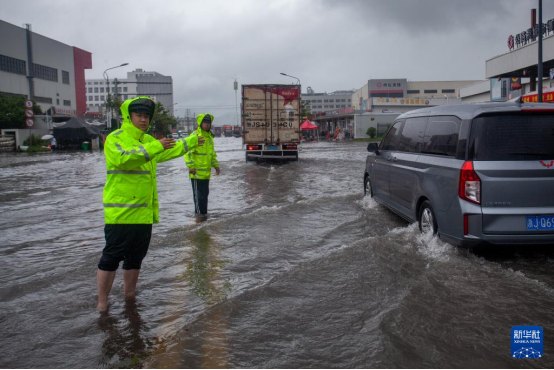 7月8日，應對臺風“丹娜絲”，浙江省臺州市公安局交警支隊直屬二大隊院橋中隊民輔警在臺州市黃巖區院橋鎮一路段積水處執勤，確保道路暢通。（圖片來源：新華社）