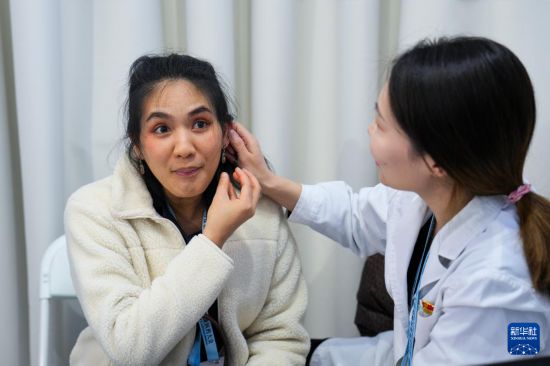 12月3日，在2024世界傳統醫藥大會的中醫藥體驗區，一名來自泰國的參會嘉賓（左）在首都醫科大學附屬北京中醫醫院的展位體驗耳穴壓豆。新華社記者 鞠煥宗 攝