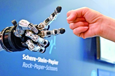 在德國漢諾威工博會上，參觀者與一款智能機器人進行“石頭剪子布”游戲。新華社發