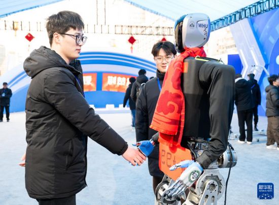 2月5日，參觀者在現場與人形機器人握手。新華社記者 肖藝九 攝