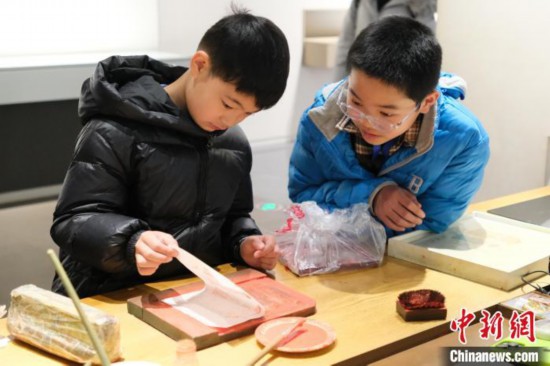 2月7日，浙江杭州，小朋友在體驗木版水印技藝。春節期間，浙江省非物質文化遺產館成為家庭出游的熱門之選，民眾在傳統技藝體驗中感受年味。中新社記者 曹丹 攝