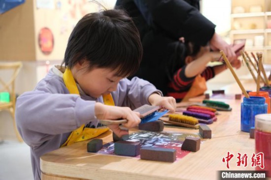 2月7日，浙江杭州，小朋友在體驗西湖綢傘的刷花技藝。春節期間，浙江省非物質文化遺產館成為家庭出游的熱門之選，民眾在傳統技藝體驗中感受年味。中新社記者 曹丹 攝