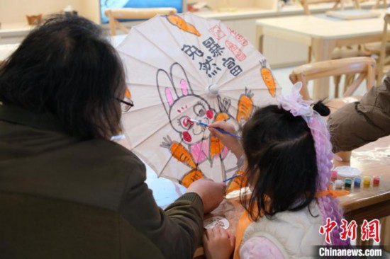 2月7日，浙江杭州，小朋友在綢布傘上體驗彩繪。春節期間，浙江省非物質文化遺產館成為家庭出游的熱門之選，民眾在傳統技藝體驗中感受年味。中新社記者 曹丹 攝