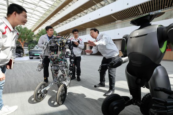 2025年2月24日，全國人大代表馮興亞（右一）在廣州向廣汽第三代具身智能人形機器人團隊工程師了解該型機器人的AI自主控制技術突破和應用場景創新情況。新華社記者 劉大偉 攝