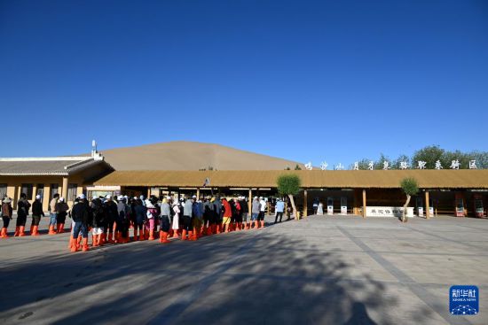 5月10日，在甘肅省敦煌市鳴沙山月牙泉景區，游客排隊進入駱駝乘騎區。新華社發（張曉亮 攝）