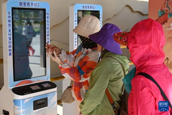 5月10日，在甘肅省敦煌市鳴沙山月牙泉景區駱駝乘騎區，游客在散客售票機上購買駱駝乘騎票。新華社發（張曉亮 攝）