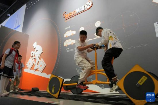 5月24日，小朋友們在山東省科技館體驗方形車輪自行車。新華社發（唐克攝）