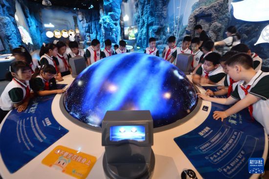 5月25日，山東省青島市市北區開平路小學學生在青島科技館參觀?！鞍l光”裝置。新華社發（王海濱攝）