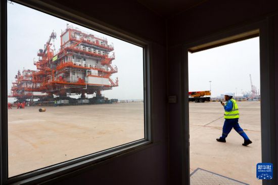 6月1日，在天津濱海新區海油工程智能化制造基地，工人指揮平臺裝船作業。新華社發（杜鵬輝攝）