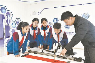 在山東日照金海岸小學，老師指導學生練習機械臂毛筆書寫編程。