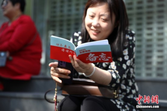 6月7日，2025年全國高考拉開帷幕。位于北京的中國人民大學附屬中學考點外，家長翻閱2025志愿填報備忘資料。中新社記者 趙雋 攝