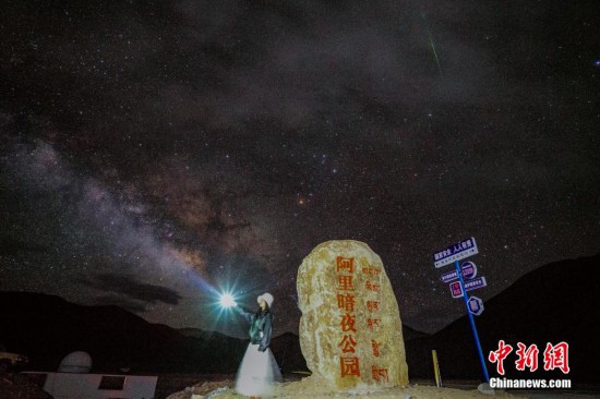 圖為6月20日晚，游客“打卡”西藏阿里暗夜公園，天上是銀河與流星（右上角）。曹枝清 攝