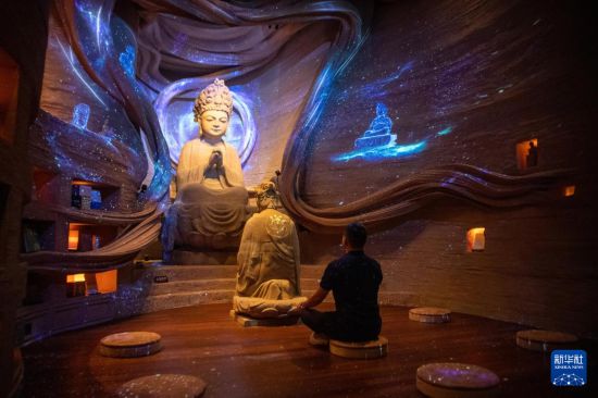 6月24日，游客在大足石刻景區一處數字化聲光場景中體驗。新華社記者 唐奕 攝