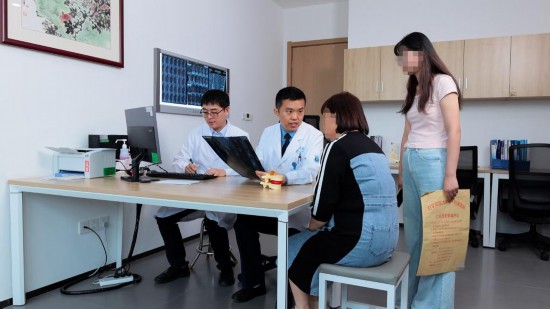 空軍軍醫大學西京醫院骨科主任黃景輝（左二）為患者解答脊柱側彎問題。新華社發