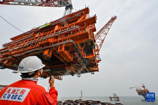 9月8日，工人在墾利6-1油田10-1北區塊Ⅱ期開發項目油氣平臺安裝作業現場指揮吊裝。  新華社發（杜鵬輝攝）