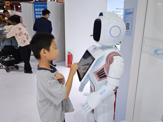 小朋友正在和陪伴型機器人互動。新華社記者劉禎 攝
