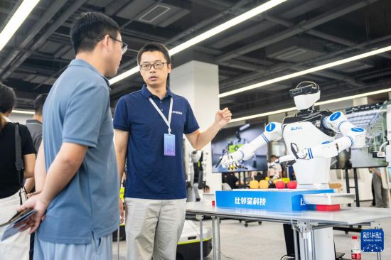9月15日，在湖南湘江新區長沙智谷，工作人員（右）在介紹一款人形機器人的分揀功能。新華社記者 陳思汗 攝