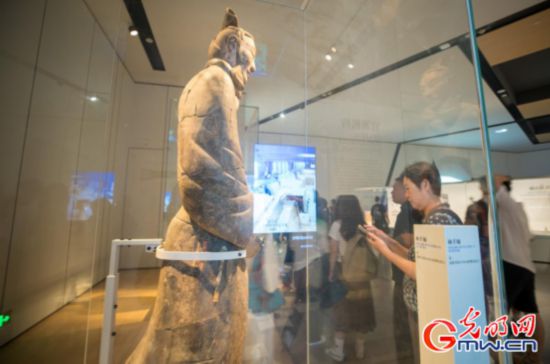 觀眾近距離參觀兵馬俑展柜，屏幕展示兵馬俑出土位置實時情況