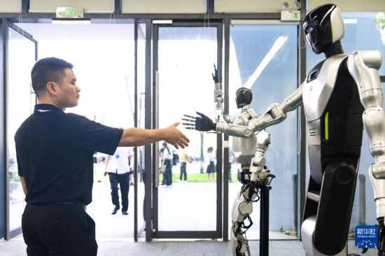 9月15日，在湖南湘江新區長沙智谷，觀眾與人形機器人握手。新華社記者 陳思汗 攝