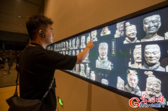 媒體團記者操作兵俑面部數據庫大屏，對比不同類型兵俑頭部