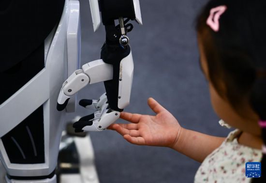 9月21日，小朋友在2025世界制造業大會智能機器人展區和一款人形機器人互動。