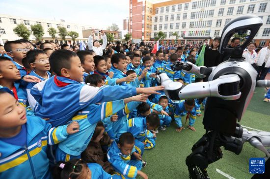 9月25日，在甘肅省定西市安定區西關小學，學生和人形機器人互動。新華社發（王克賢攝）
