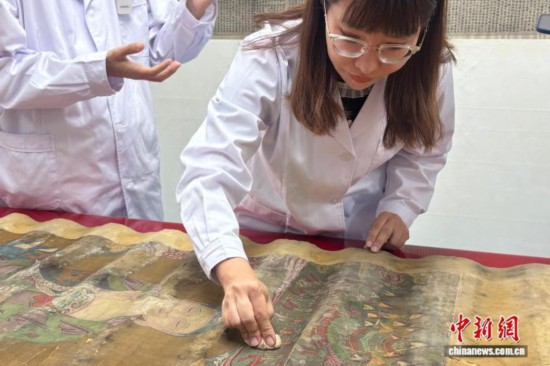 文物修復師在北京大運河博物館用傳統方法對灰塵污漬嚴重的書畫進行粘附除塵。 中新社記者 徐婧 攝