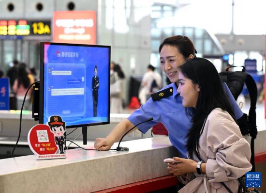 10月5日，在河北石家莊火車站候車大廳服務臺，旅客向“AI智能客服機”問詢旅行信息。     新華社發（陳其保攝）