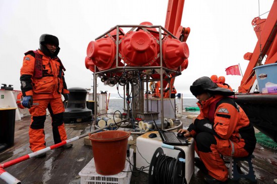 圖為劉坤（右）等科考隊員和剛回收到船上的海底生物影像觀測系統。新華社記者劉詩平 攝