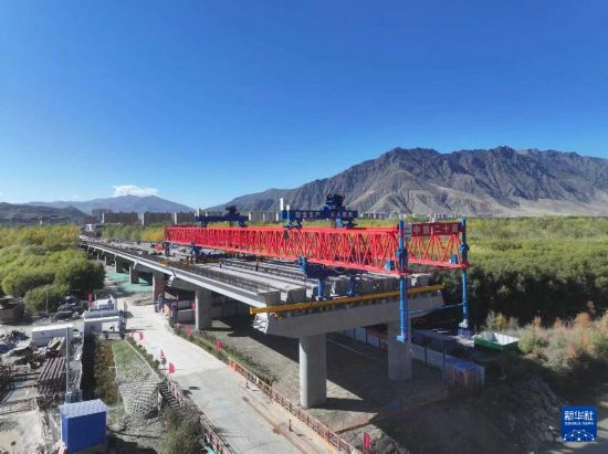 施工人員在架設薩熱路跨江大橋的最后一片預制箱梁（無人機照片，10月13日攝）。     新華社發（帥卿 攝）