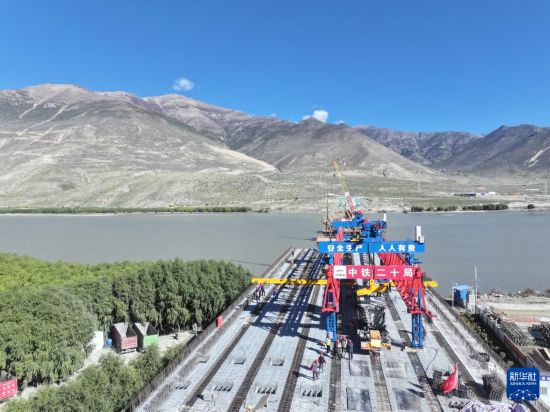 施工人員在架設薩熱路跨江大橋的最后一片預制箱梁（無人機照片，10月13日攝）。新華社發（帥卿 攝）