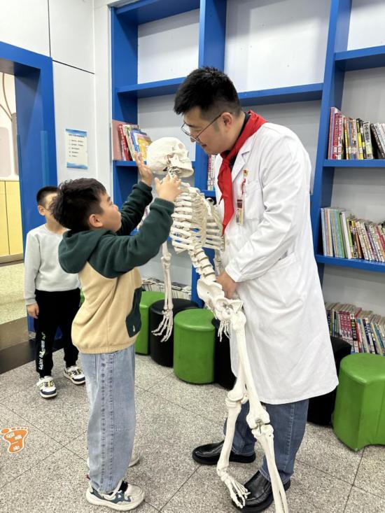 北京協和醫院骨科主治醫師楊陽利用骨骼模型，向學生科普脊柱知識。（北京協和醫院西單院區供圖）