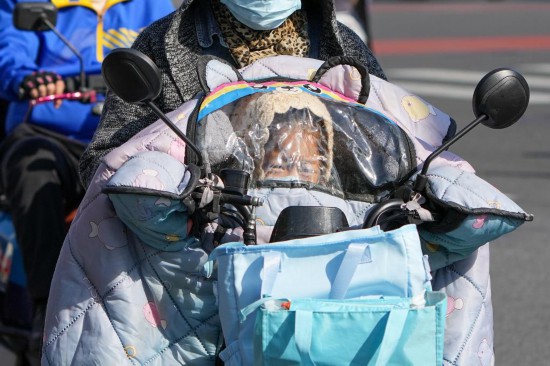 10月18日，一位小朋友在電動自行車的擋風后面躲風。新華社記者 鞠煥宗 攝